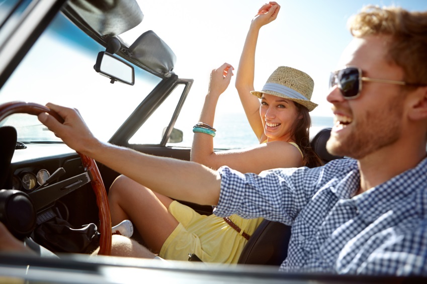 A happy young couple driving in a convertible on a bright summer's day